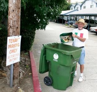 Man dumping organics material collected in a smaller container into an open organics cart which will be serviced.